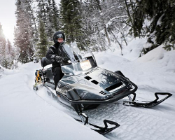 Мужчина едет по лесу на снегоходе Yamaha Viking 540