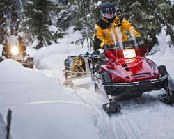 Люди едут по лесу на снегоходе Yamaha Viking